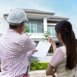 An inspector and a homeowner or buyer examining a building inspection report at a property.