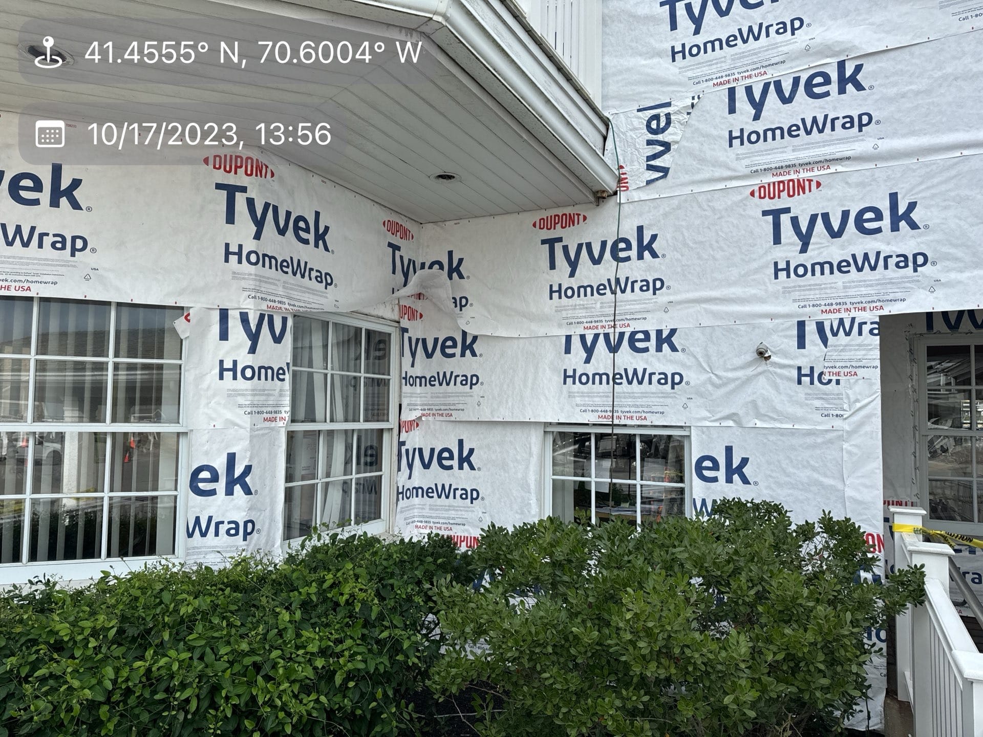 2023-10-17 17 56 42Z-lnumlz87orpjwky7 Building exterior covered in Tyvek HomeWrap with white windows and shrubs.
