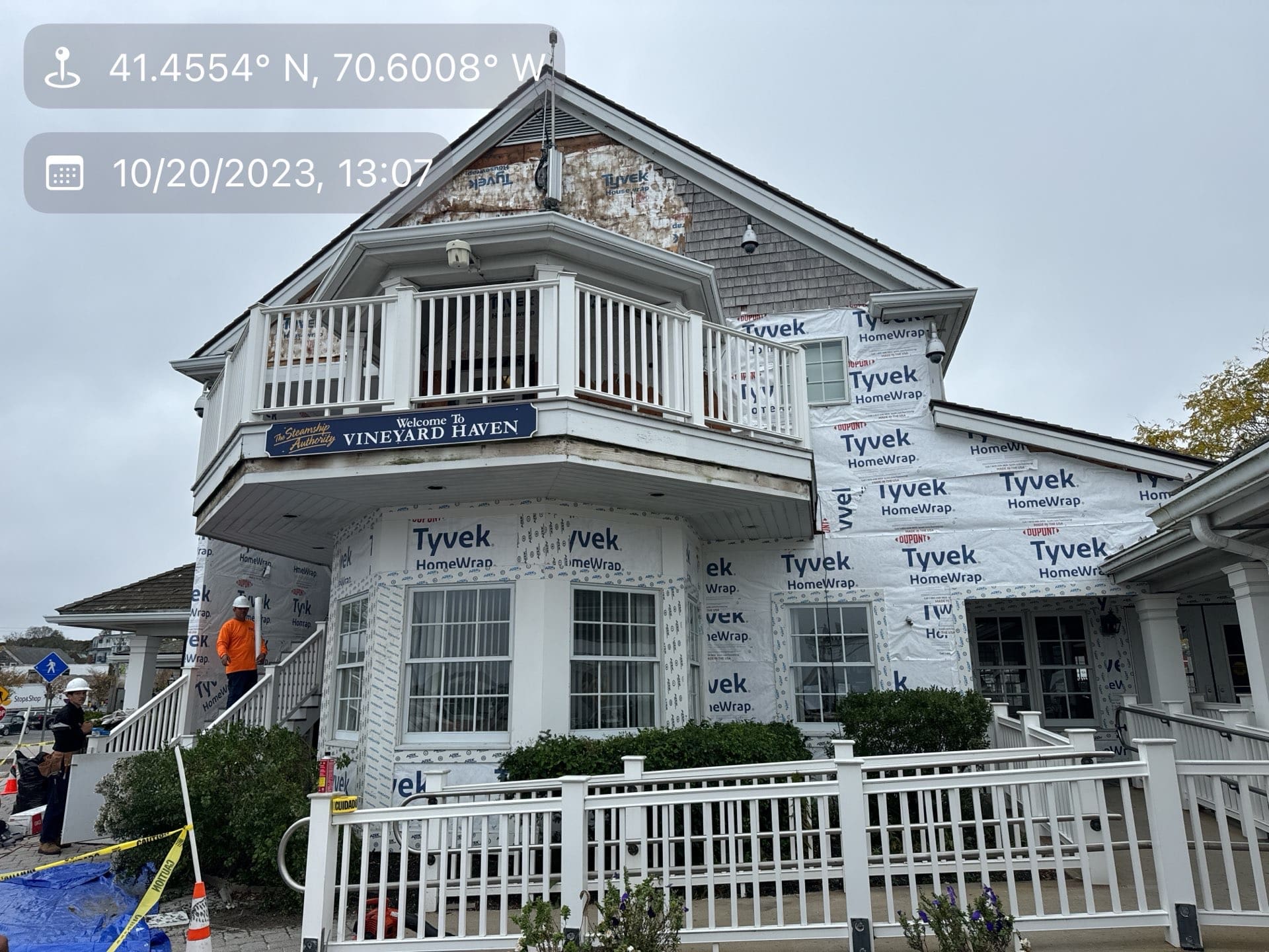 2023-10-20 17 07 27Z-lnyv67lj2af0hjjz Building under renovation wrapped in Tyvek, featuring a white balcony and worker.