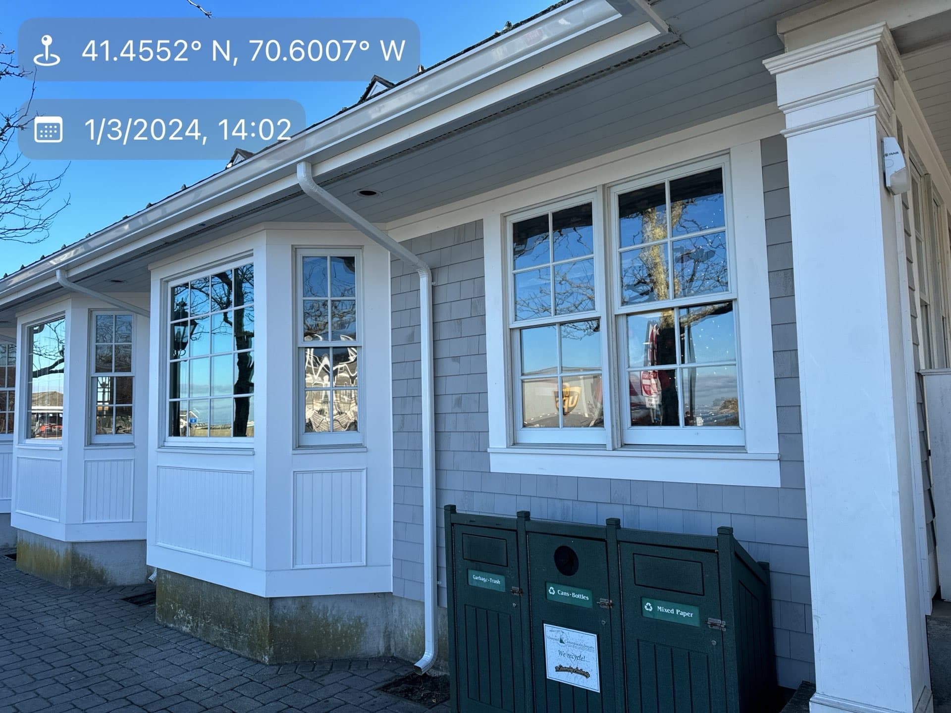 2024-01-03 19 02 03Z-lqy5agvhspq4r1a5 Gray shingle building with three white bay windows and a green recycling bin.