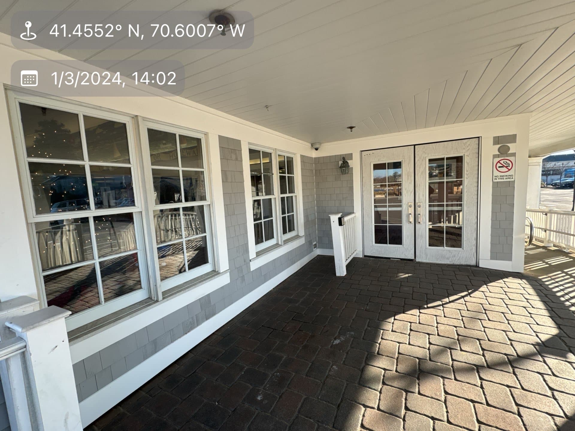 2024-01-03 19 02 10Z-lqy5amkxlganaya1 Covered patio entrance with gray shingle siding, brick pavement, and double glass doors.