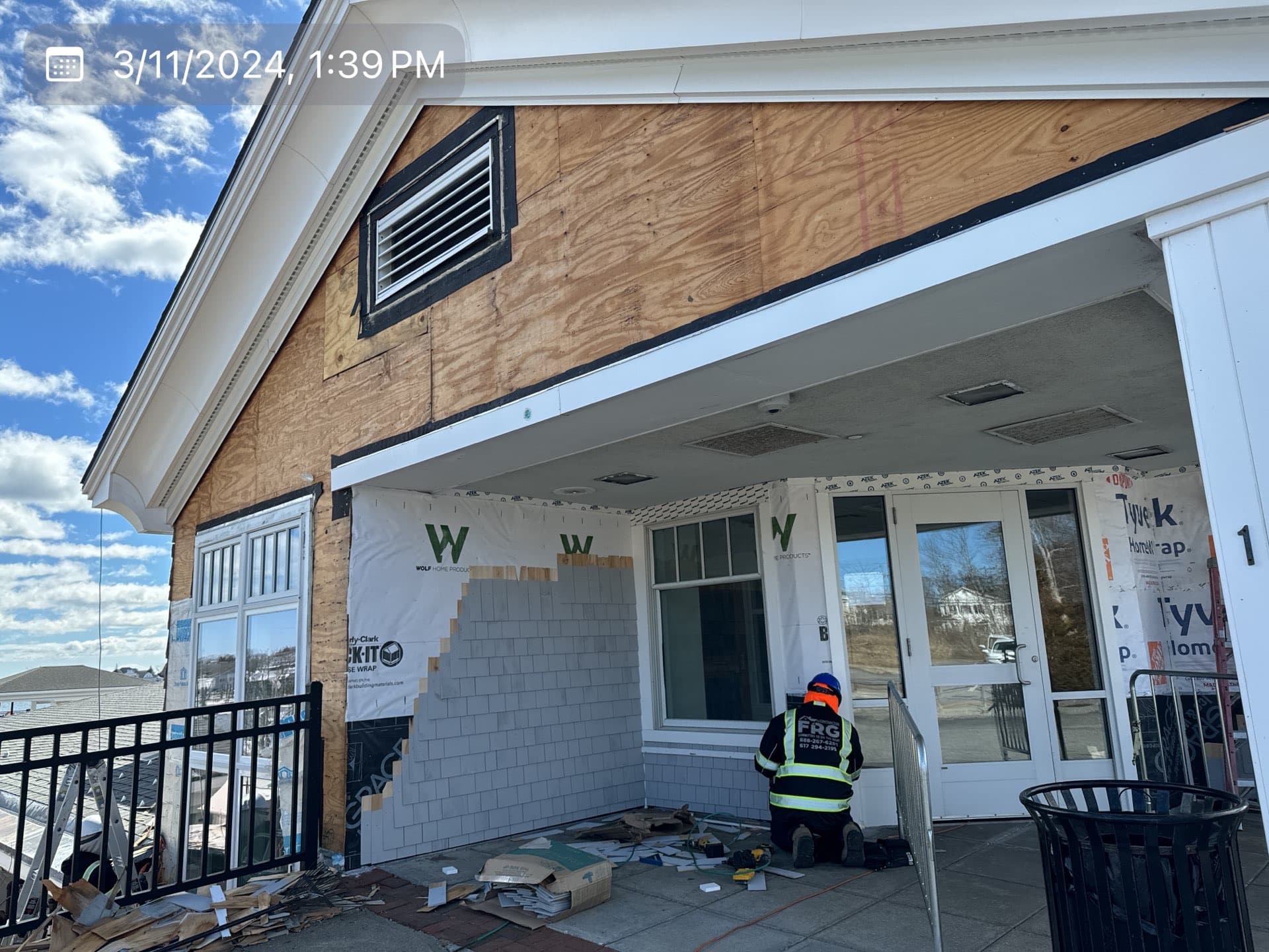 2024-03-11 17 39 51Z-ltn8ap4l6dy5rtwp Construction worker installing gray shingle siding on a partially exposed plywood wall.