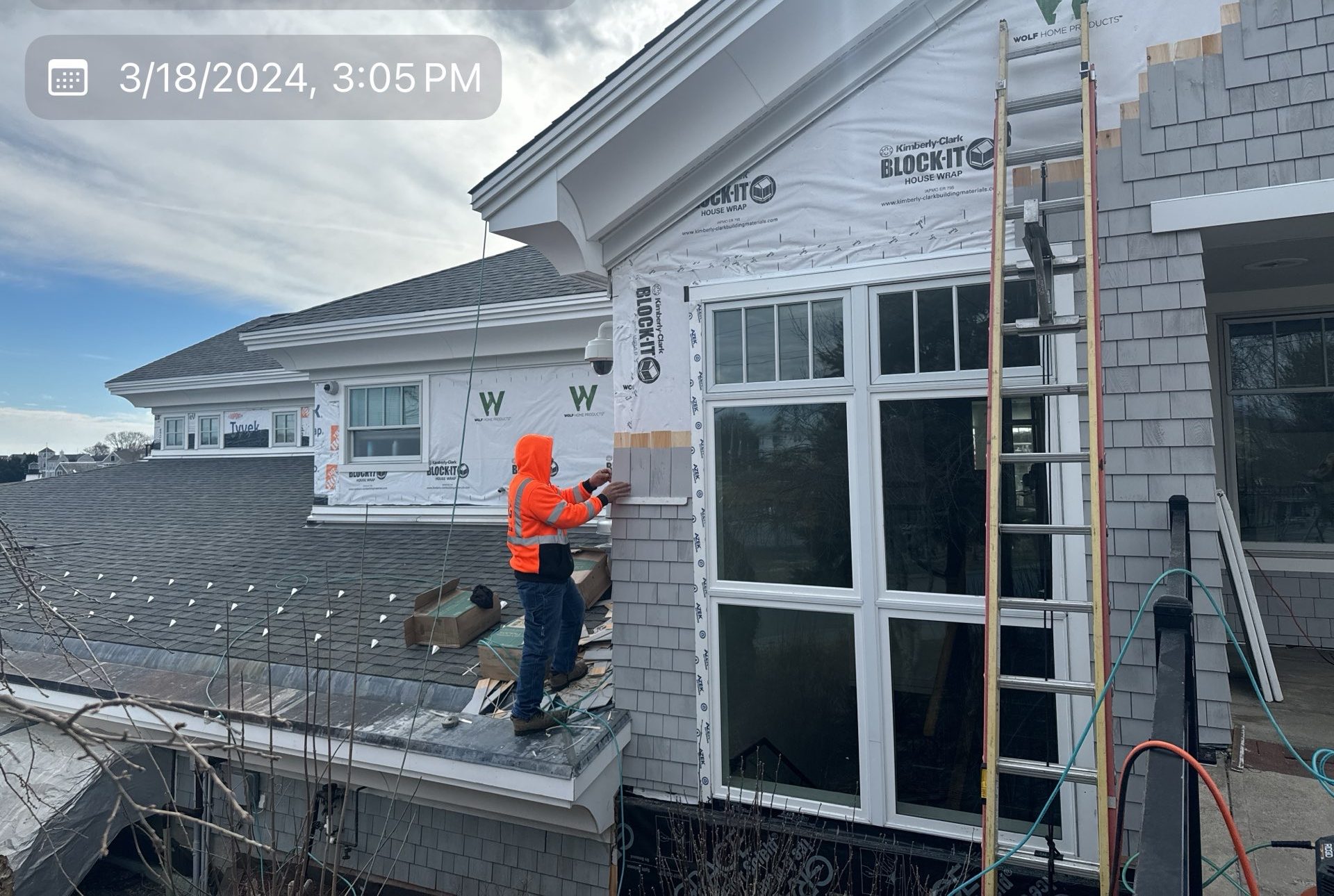 2024-03-18 19 05 24Z-ltxbfocscr6w92ub Construction workers installing siding on a building wrapped in Tyvek.
