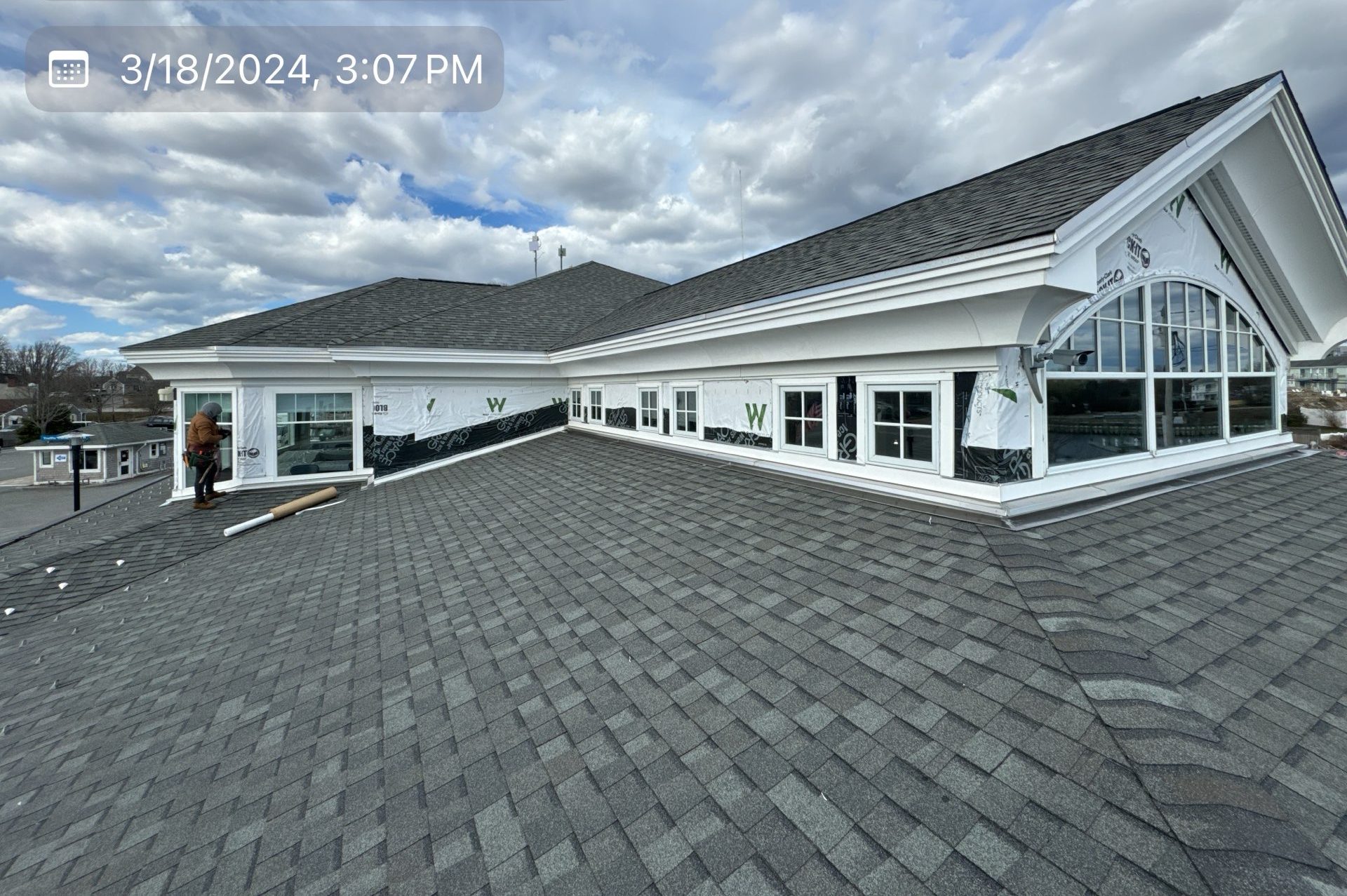 2024-03-18 19 07 49Z-ltxbisadvps18ex10 Roof view of a building with new shingles and side walls wrapped in house wrap.