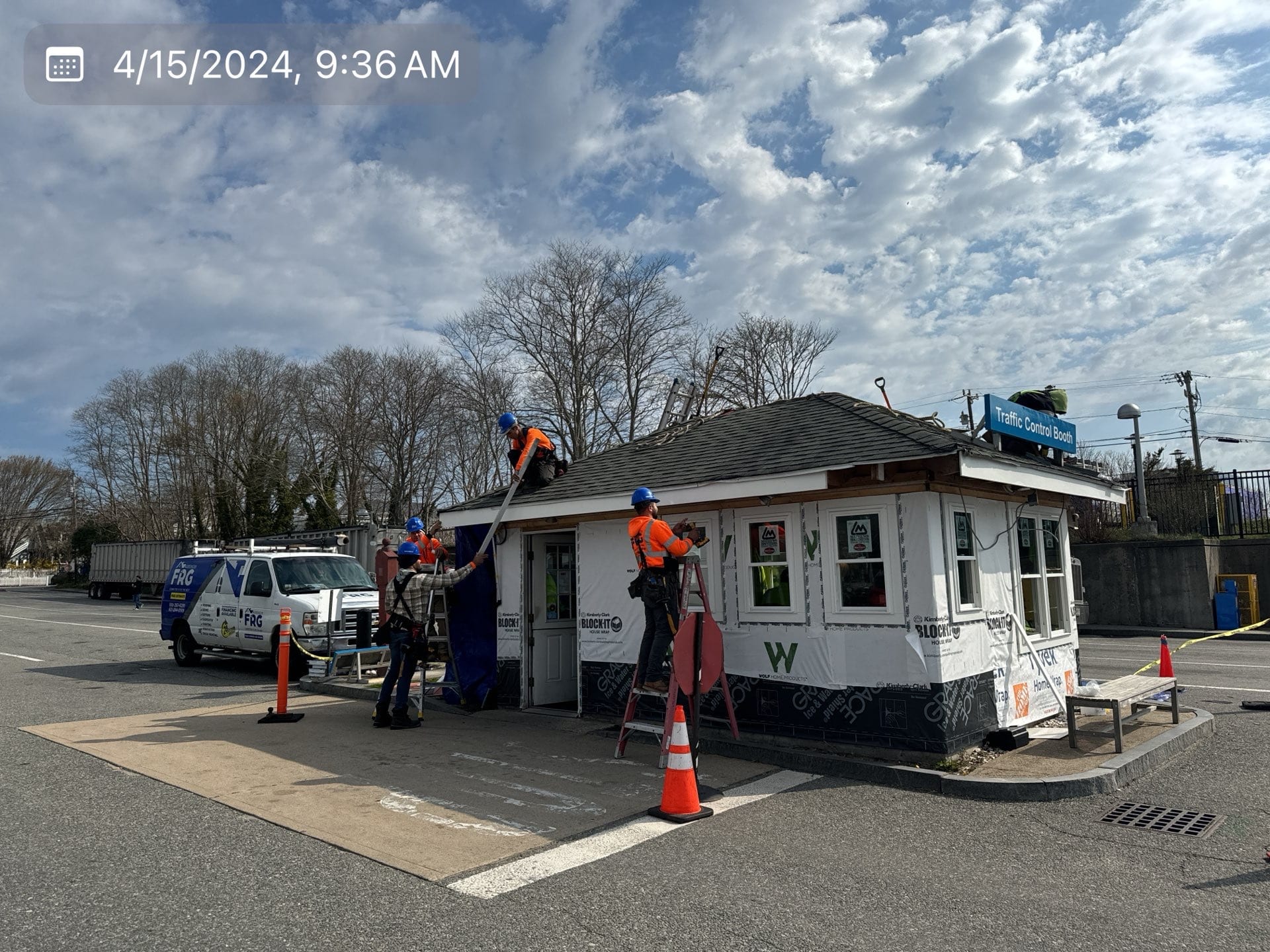 2024-04-15 13 36 20Z-lv100c1b526di5sv Construction workers applying house wrap to a small traffic booth.