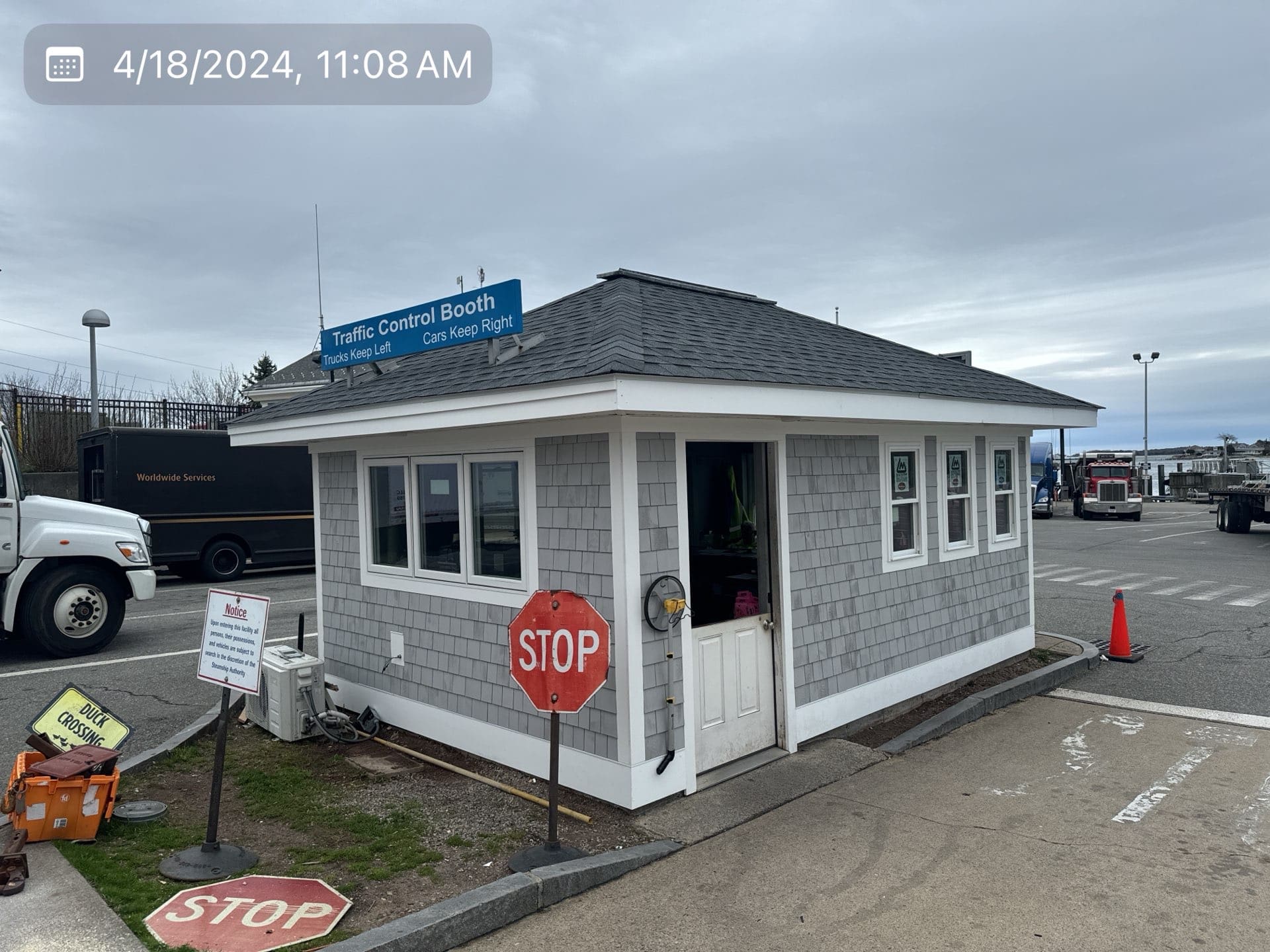 2024-04-18 15 08 55Z-lv5dmyp9g1tzhnoe Small traffic control booth with gray shingle siding and a stop sign outside.