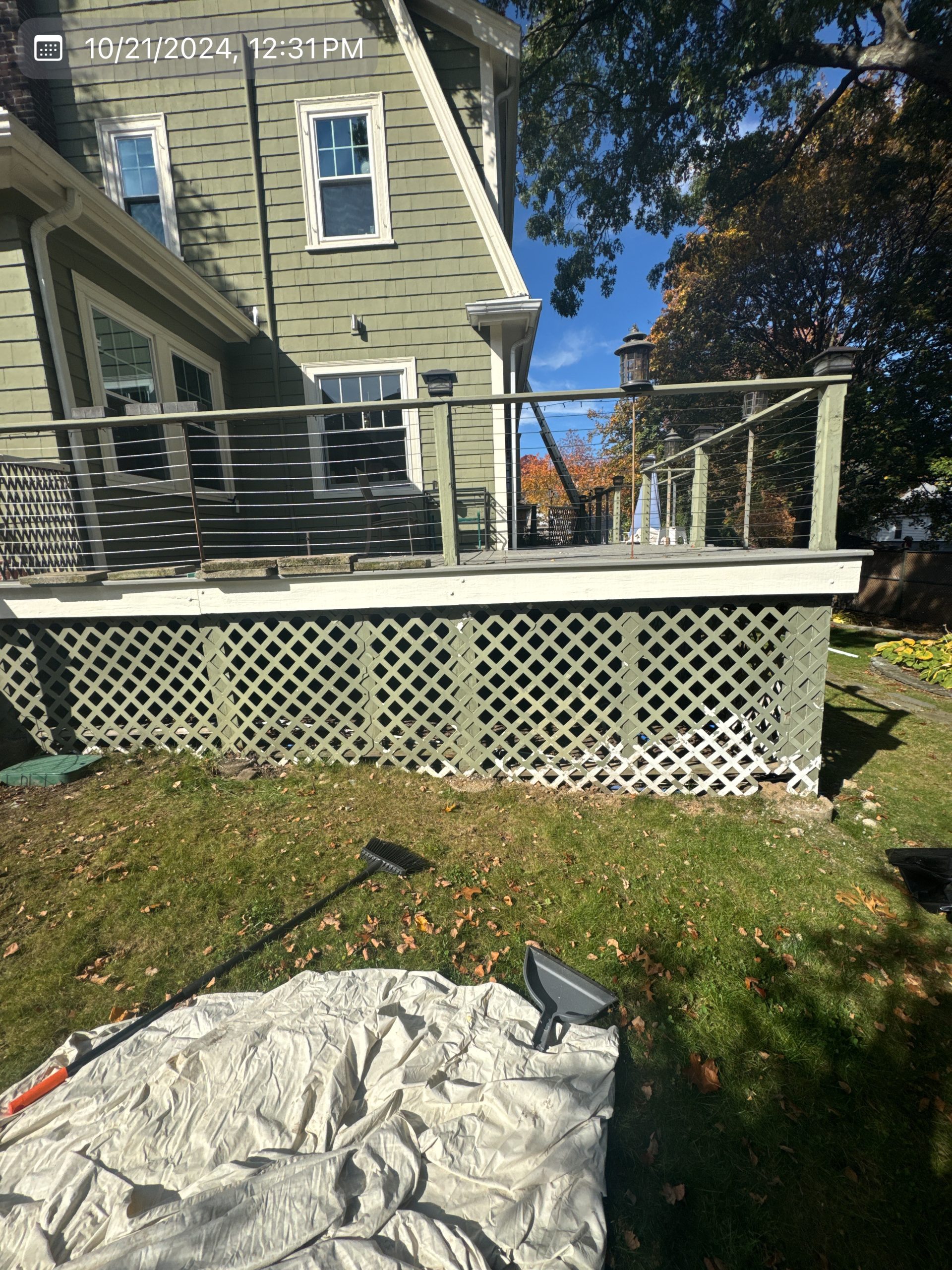 2024-10-21 16 31 11Z-m2j8h6wiebmte3ai House with a large deck and lattice skirting, seen from the grassy backyard under a bright blue sky.