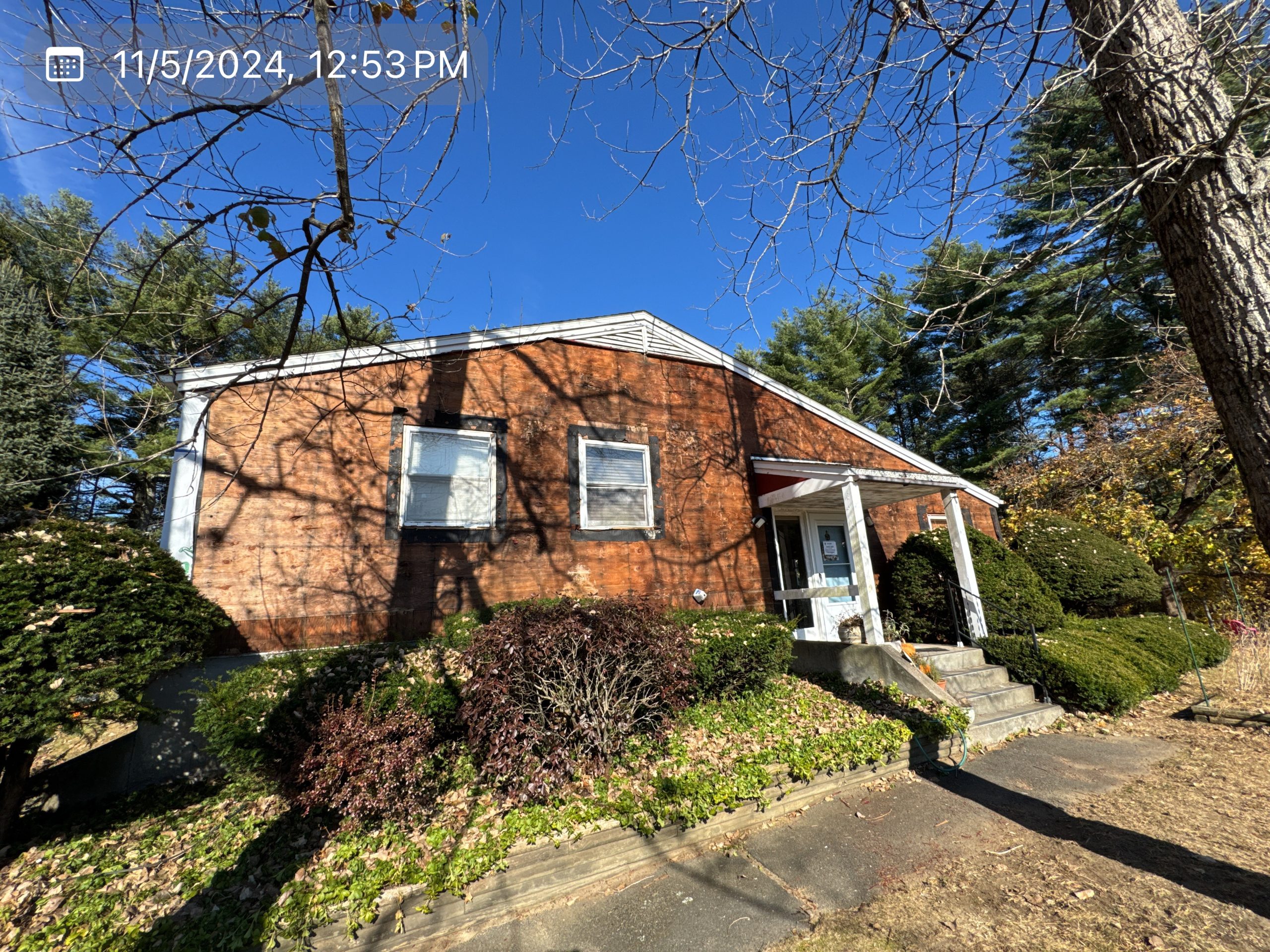 2024-11-05 17 53 15Z-m34r0ijj6mdghvum Red brick house with white trim, small porch, and front steps under a clear blue sky.