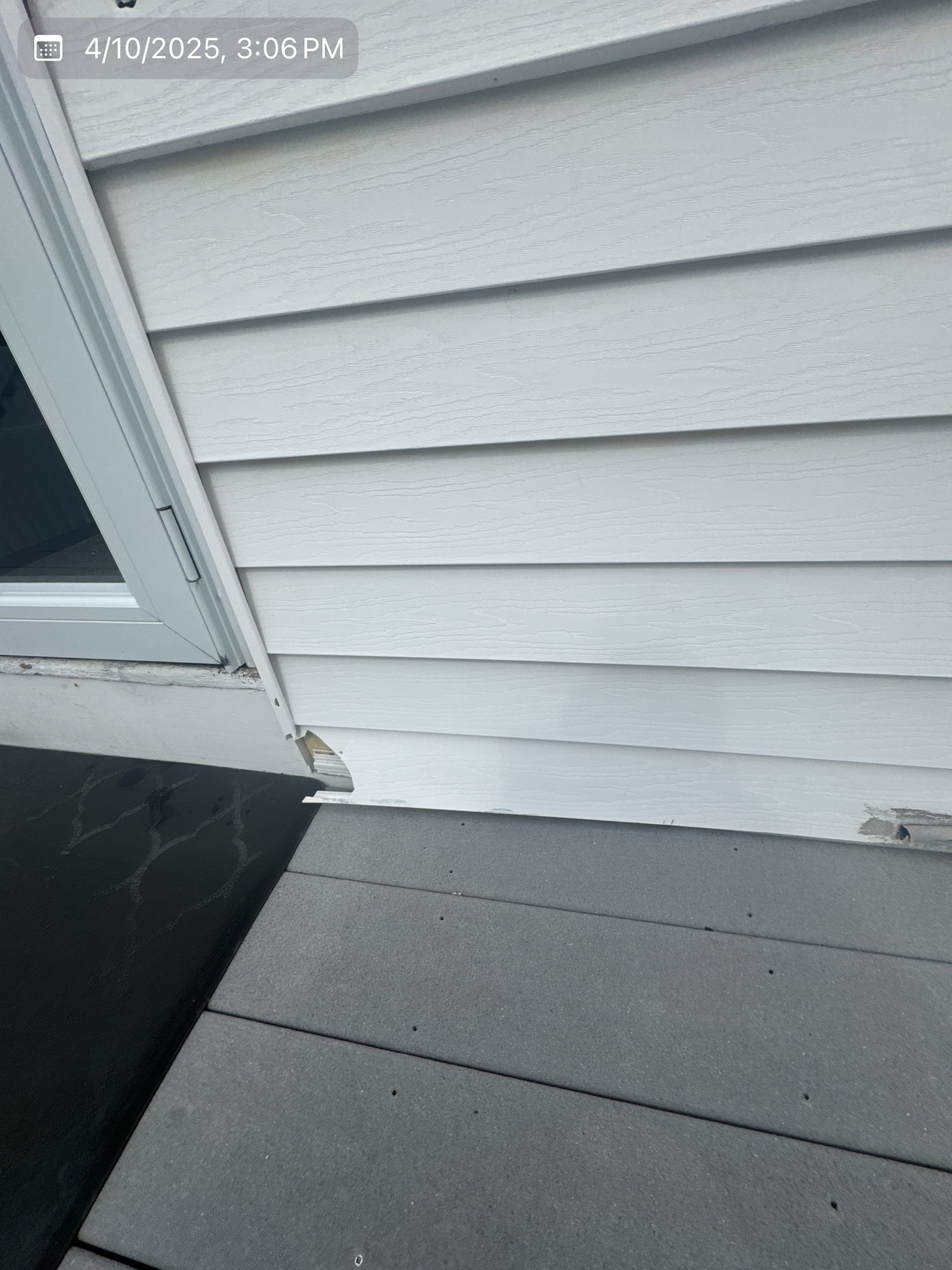2025-04-10 19 06 21Z-m9bqbf4emf3aopqg white horizontal siding showing minor damage near the bottom edge where it meets a gray composite deck.