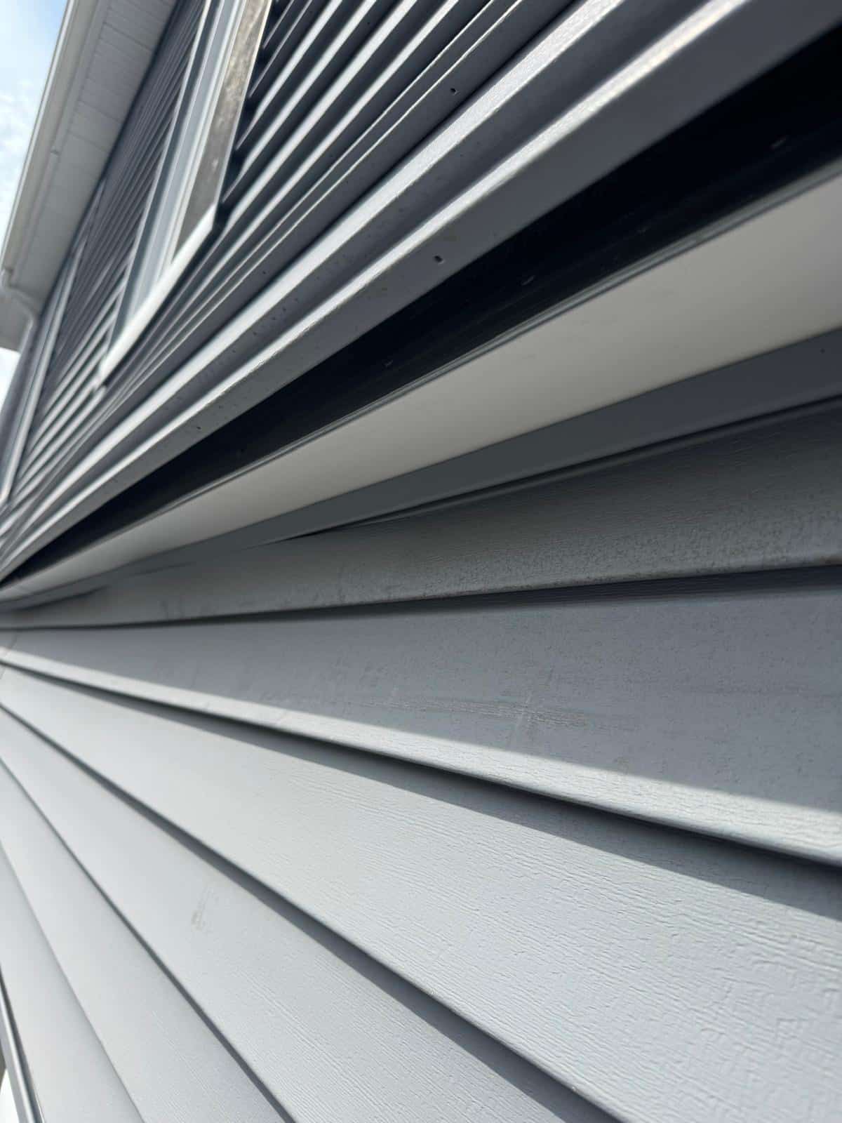 2025-04-22 12 47 29Z-m9si2f1ffv2n7r44 light gray horizontal vinyl siding, viewed at a sharp upward angle, showing the texture and overlapping panels.