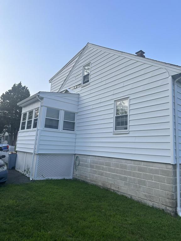 7 24 2023 9 10 20 PM-lkhlo86h51dk4ljz Side of a white vinyl-sided house with a sunroom and cinder block foundation.
