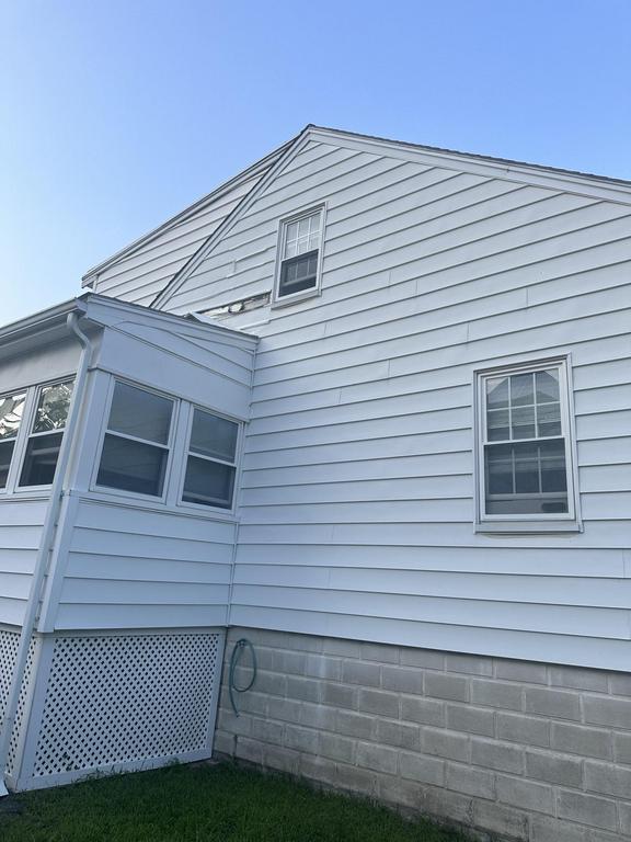 7 24 2023 9 10 20 PM-lkhlo86isqcd9fq10 Side of a white vinyl-sided house with a sunroom and cinder block foundation.