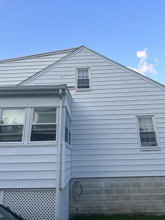 7 24 2023 9 10 20 PM-lkhlo86nkth3pq14 Gable end of a white sided house with a single window against a blue sky.