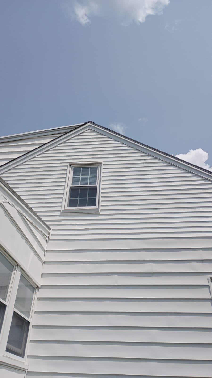 8 3 2023 1 18 15 PM-lkvf7ndile5llu74 Gable end of a white sided house with a single window against a blue sky.