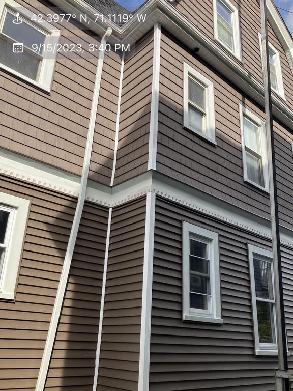 9 15 2023 3 40 18 PM-lml07y8652uul1d5 Exterior corner of a multi-story house covered in new brown horizontal and shingle-style siding with crisp white trim and a white downspout.